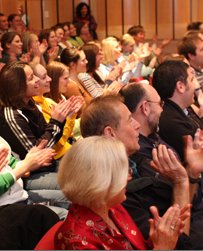 20210726_SupporttheLibraries_Applause_010 Crowd of people sitting in an auditorium smiling and applauding