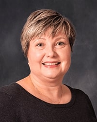 Daniela Richter portrait showing head and shoulders, smiling, on a gray background