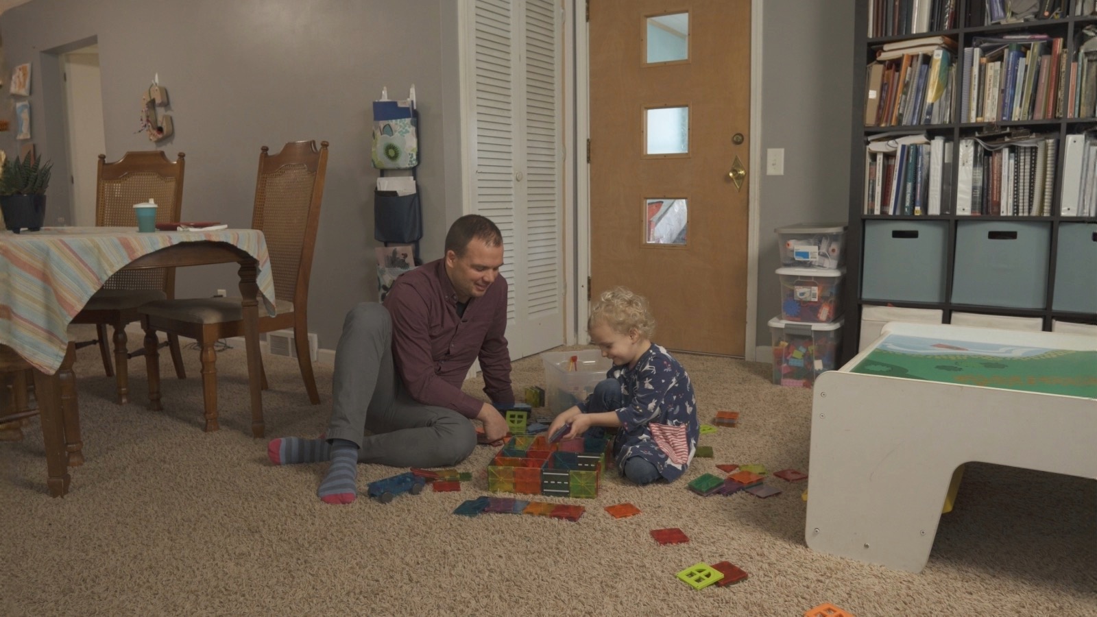 A man and child playing with colorful blocks on the floor.