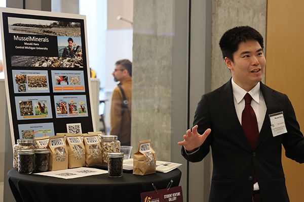 Photo of a student standing next to a hightop table during the New Venture Challenge event