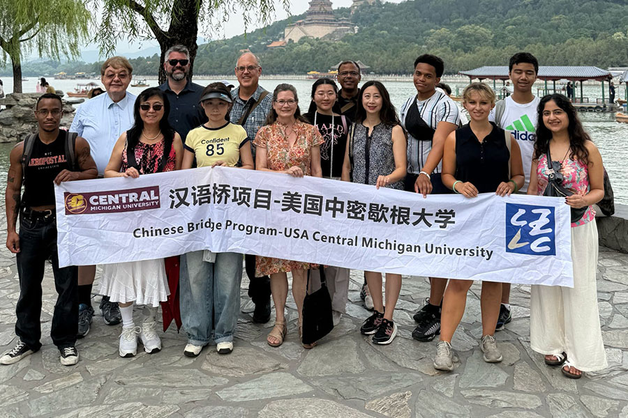 Students and faculty rom the CBA stand with Chinese counterparts from the Zhejiang University of Technology. They hold a banner tin Chinese and English that reads Chinese Bridge Program-USA Central Michigan University. Behind them is a river and temple.