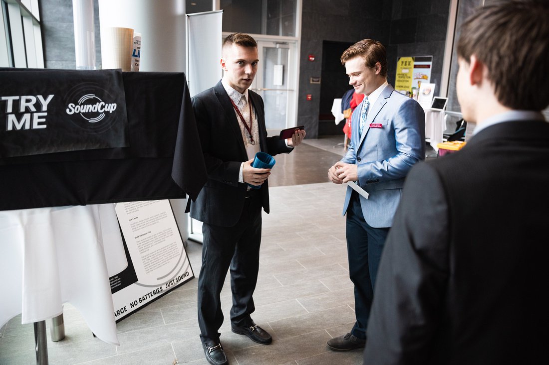 Three people dressed in business attire standing and talking.