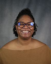 Woman in brown top with glasses.