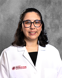 A female CMU College of Medicine medical student wearing her white coat as she smiles for the camera.