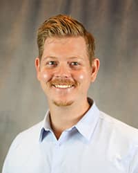 Headshot for Joseph Jolly wearing a light blue button up shirt.