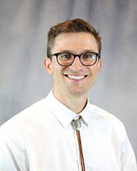 Headshot of Justin Morin wearing a white button up shirt.