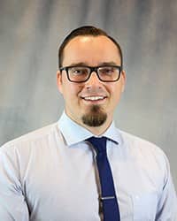 Headshot of Arthur Sieron wearing a light blue shirt with a dark blue tie.