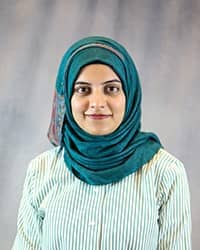 Headshot of Syeda Zehra wearing a green blouse and a teal hijab.