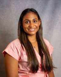 A woman with long hair wearing a pink shirt.