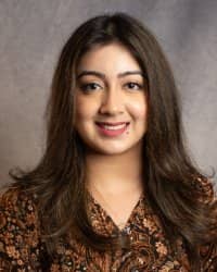 A women with long brown hair smiling in a brown patterned blouse.