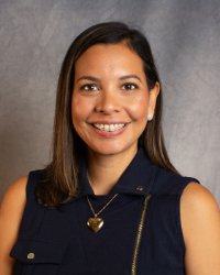 A woman wearing a black tank top and gold heart necklace.