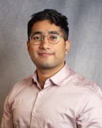 A man wearing glasses and a pink shirt.