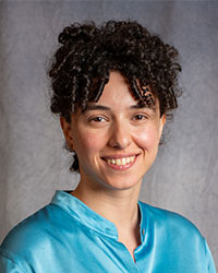 Elene Japharidze is wearing a blue satin shirt and has curly hair.