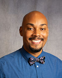 Jamie Scott is wearing a blue button down shirt with a print bowtie.