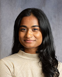 Emylin Thomas is wearing a beige turtleneck blouse.