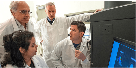 Dr. Rossignol (seated right), with collaborators Dr. Dunbar (rear right), Dr. Sharma (rear left) and grad student (seated left) work together on an interdisciplinary project researching Huntington’s disease.