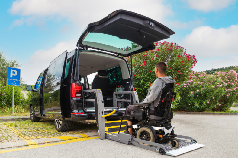 A man in a wheelchair using a wheelchair lift to access the van.