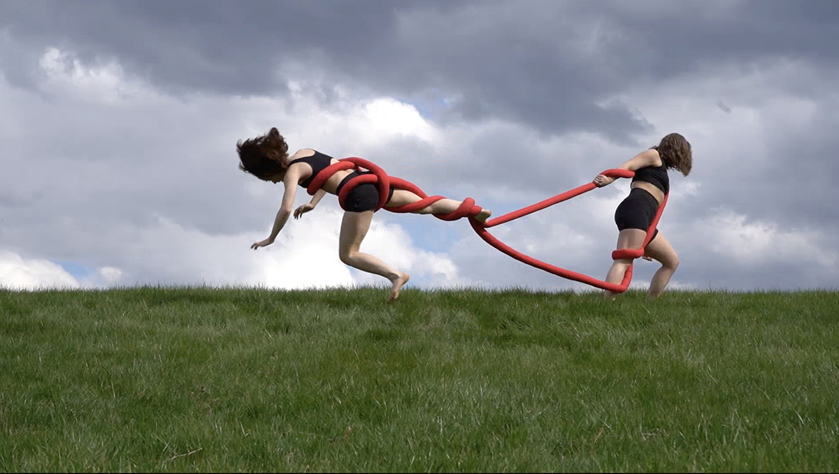 Babyknots, Two performers interact with an amorphous red tube through a series of knotted and winding interactions.
