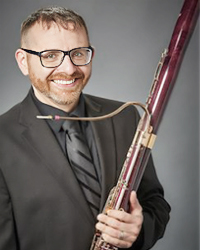 Headshot of Derek Bannasch on a grey backdrop. He's holding his bassoon.