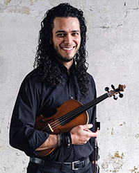 Matheus Garcia Souza smiling while holding a violin for a professional headshot against a white background.