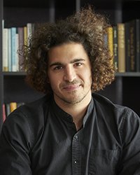 Headshot of Marco Schirripa in front of a bookshelf.
