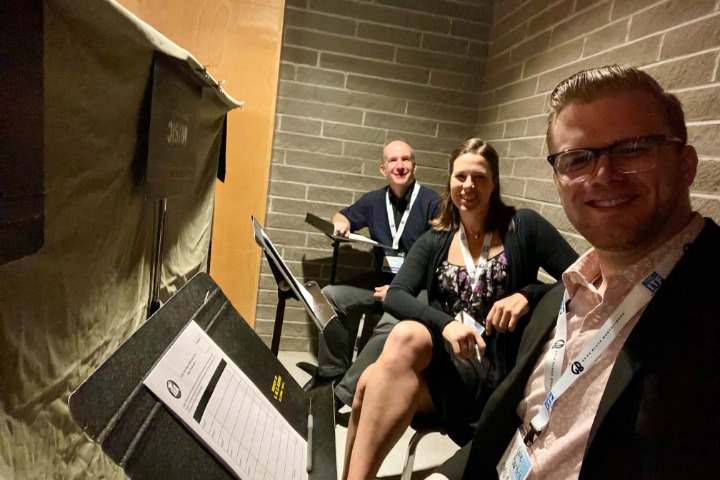 a group of people sitting in chairs smiling at the camera with music stands in front of them