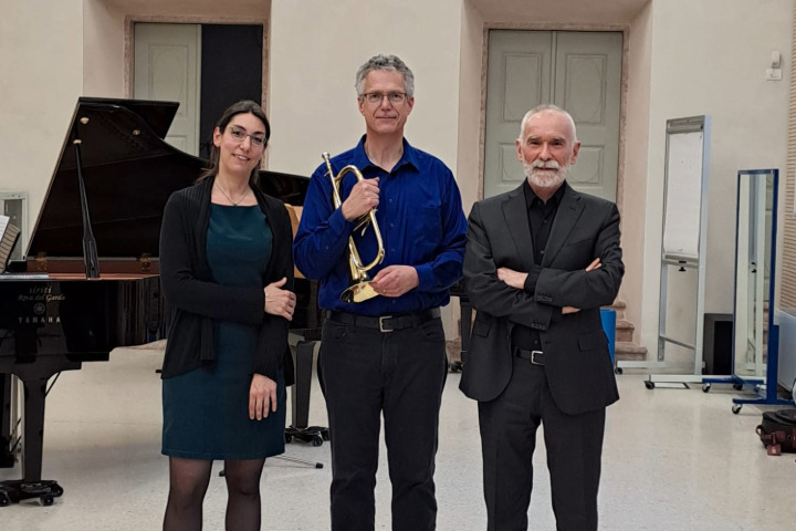 3 Individuals smiling and dressed in concert performance attire. From left to right stands Francesca Carola, pianist, Neil Mueller, trumpet, and Ivano Ascari, trumpet.