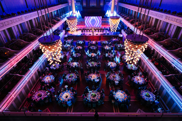 a group of people sitting at tables in a large room with chandeliers