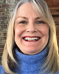 Headshot of Jeanne Ambrose in front of a brick wall.