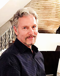 Headshot of Ken Gal. There's a staircase and vase behind him.