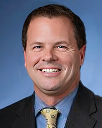 Headshot of Tony Cervone on a blue backdrop.
