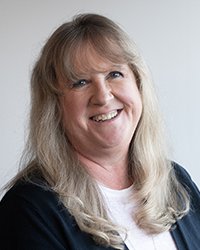 Headshot of Leanna Smith wearing a dark blue blazer and white shirt against a light grey backdrop.