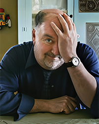 Headshot of Mike Green. He has his head in his hand as if he's embarrassed