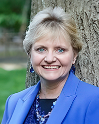 Headshot a Sheila Gruber McLean. She is leaning against a tree.