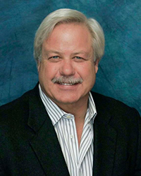 Headshot of Jim Johnson, also known as JJ, in front of a deep blue backdrop.