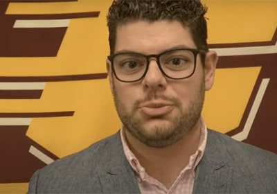 Headshot of Alum Zach Huffman in front of a backdrop displaying the flying C.