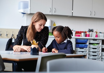 A school counselor sitting with a young student in a classroom.