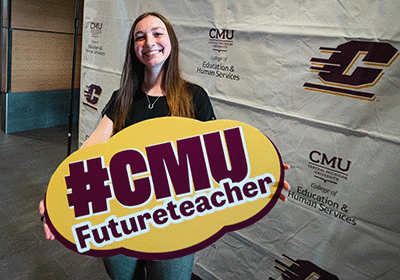 Future Central Michigan University educator holding a CMUFutureteacher sign.