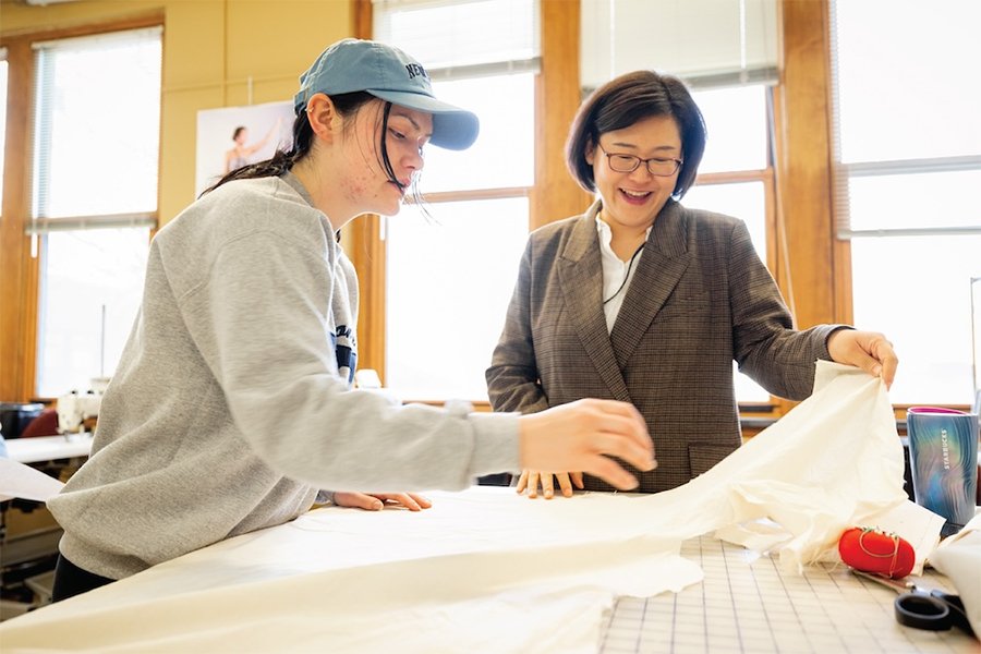 Dr. Su An and a fashion student assessing fabric in the sewing lab.