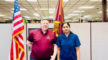 Saraswathi Nemani  and Dr. Jon Hummiston pose in an Online and Innovation office with an American flag and a maroon CMU flag in the background.