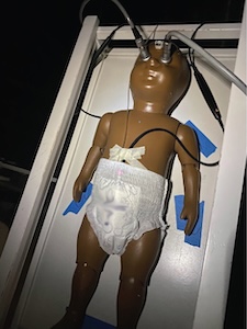 A diaper being tested on the thermal manikin, Lumi, who is laying down on a table.