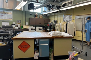 CMDT design table with clothes and various design tools in the background.