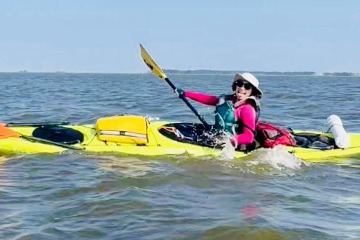 Chloe Straub in a yellow kayak in a lake.