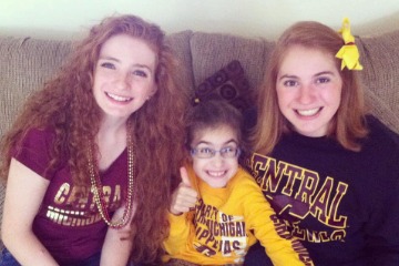Alexis Gostlin, Chloe Straub, and Sarah Spearing all wearing CMU gear posing for a photo while sitting on a couch.