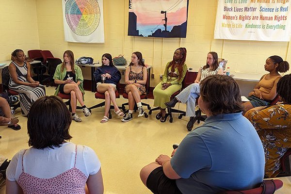 A group of students sit in chairs facing each other in a large circle