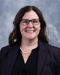 Daelyn Woolnough wears a black blazer and blouse while smiling for a headshot.