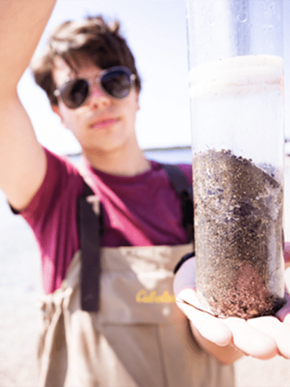 Biology student holding a Great Lakes wetlands sediment sample.