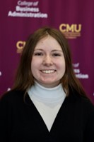A woman with brown hair standing in front of a maroon backdrop.
