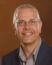 Brad Fahlman wears a button up shirt and jacket while smiling for a headshot.