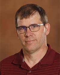 Dale LeCaptain wears a red polo shirt while posing for a headshot.